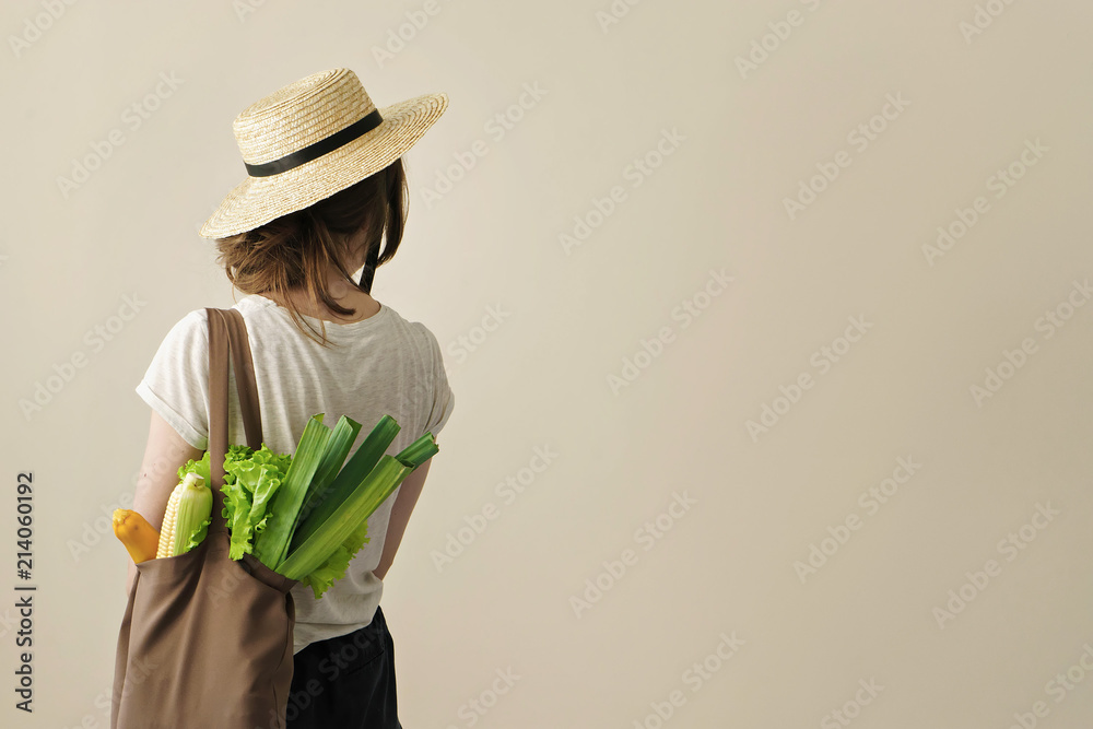 young woman holding textile grocery bag with vegetables