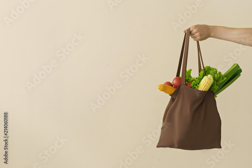 man hand holding cotton grocery bag with vegetables