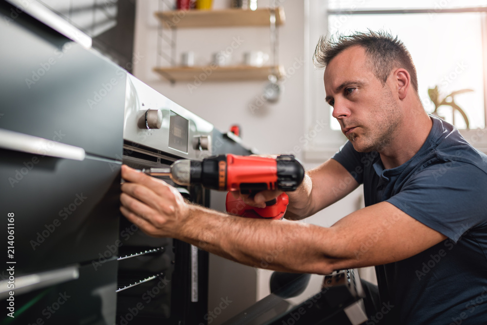 Man building kitchen and using a cordless drill Man building kitchen and using a cordless drill