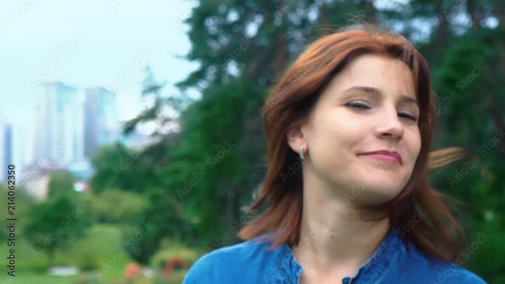 Portrait of a red-haired girl on a background of a green park shakes her hair. Face close-up. Young girl fooling around. Positive emotions Portrait of a red-haired girl on a background of a green park shakes her hair. Face close-up. Young girl fooling around. Positive emotions