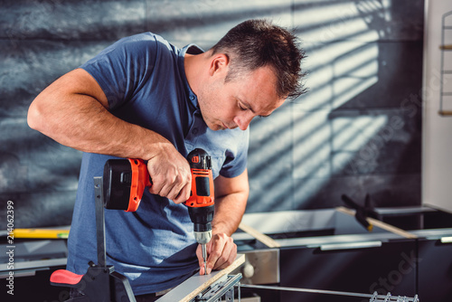 Cuadro en lienzo Woman building kitchen and using a cordless drill