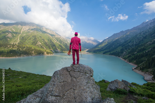 businessman in a red suit on top of a mountain in the background of a mountain lake Big Almaty Lake
