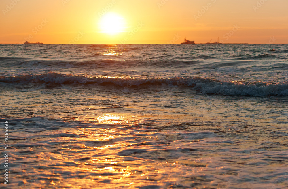 Sunset over the sea. Reflection of sunlight in the sea waves. Red sky in the rays of the sunset.