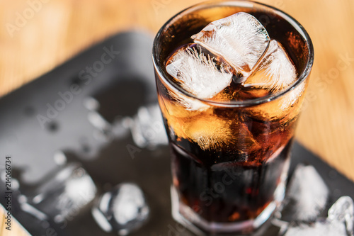 Cola with ice cubes and bubbles in glass.