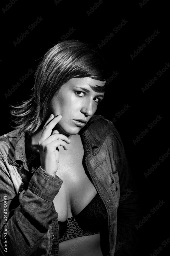 Beautiful mysterious woman in darkness looking dramatic. Portrait on black background. Converted to black and white, grain added. Beautiful mysterious woman in darkness looking dramatic. Portrait on black background. Converted to black and white, grain added.
