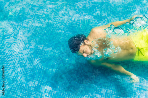 Top view of a young man floating underwater in swimming pool