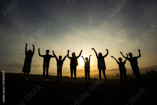 Silhouette of children jumping, happy and fun in the morning grassland, sunrise in nature.