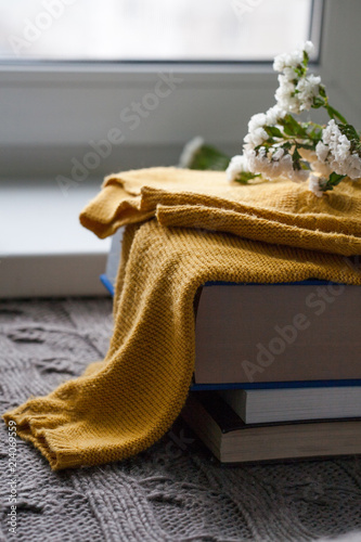 Details of still life in the home interior. Sweater, cup, wool, cozy, book, candle. Moody. Cosy autumn winter concept. Copy space