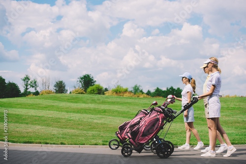 side view of female golfers with golf equipment walking at golf course