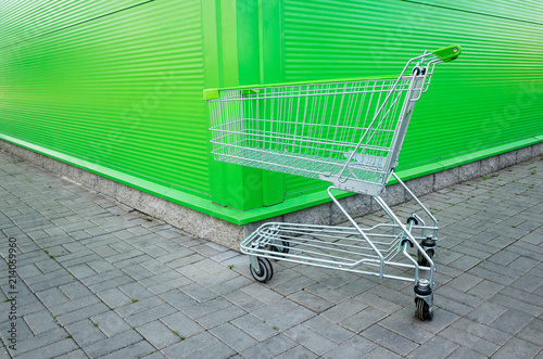 Empty shopping cart parking on green background with copyspace. retail store. © Ivan Uralsky