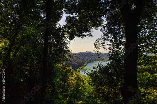 view of the lake of Albano among the branches of the trees, tourist area of the Roman castles, Rome Italy