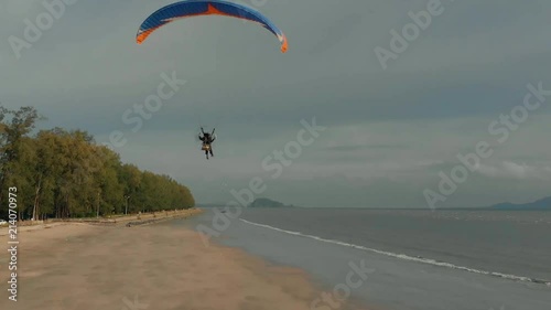 Close-up paramotor flies away along the sandy beach in slow motion. Background with islands view. The coast of Thailand. Trang province. Sikao. Paraglide. Para motor photo