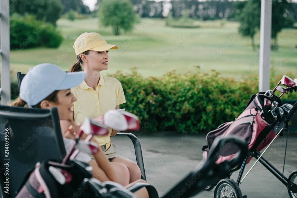 side view of women in caps resting after golf game at golf course