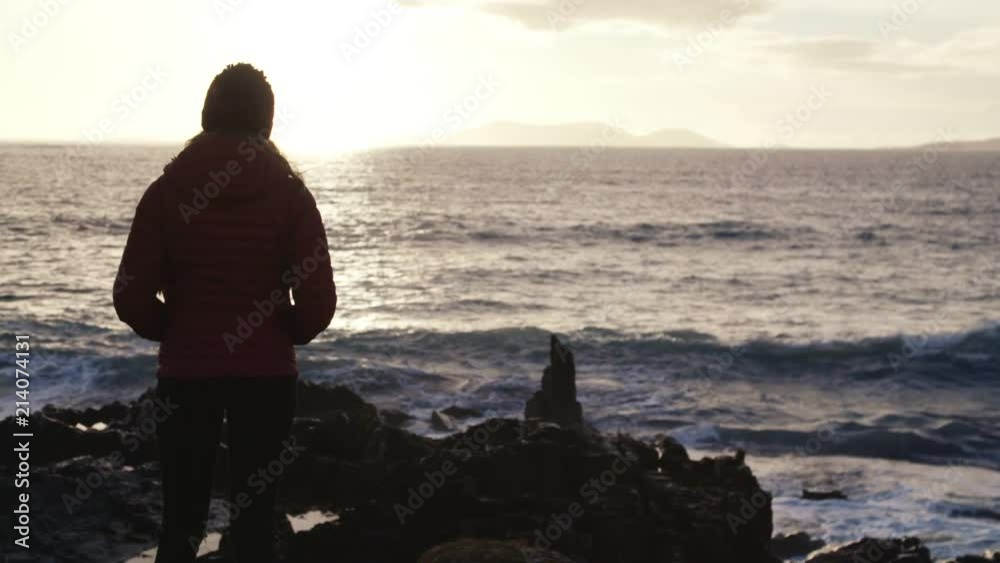 Hiker girl looks out at the sunset over the West coast of Ireland. Hiker girl looks out at the sunset over the West coast of Ireland.