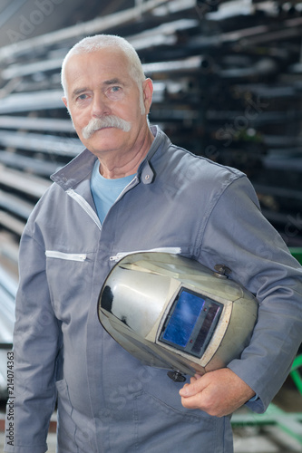 portrait of older male steel worker welding with protective mask