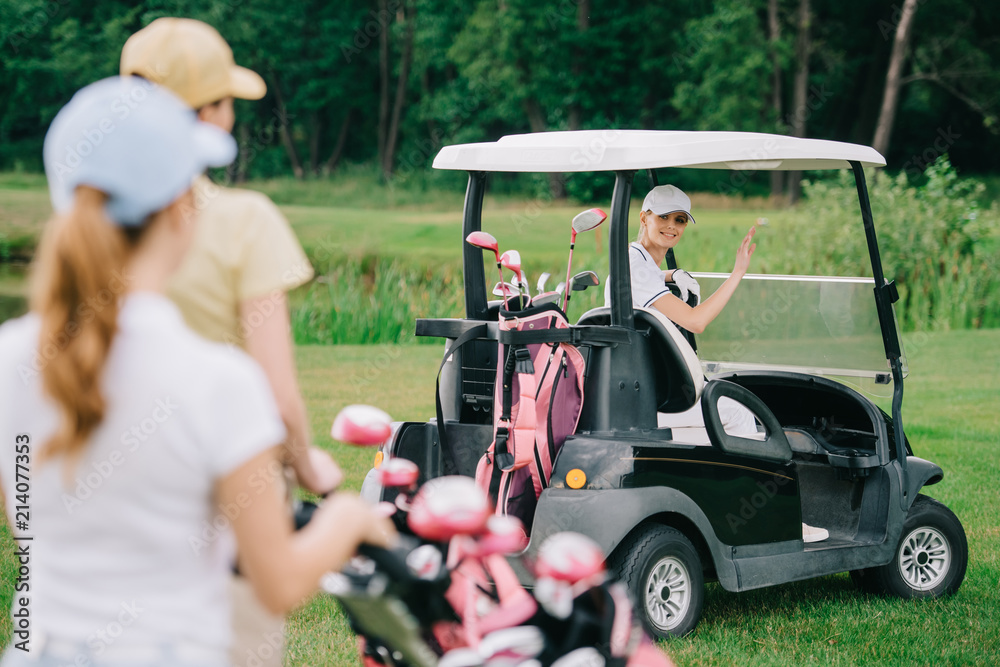 selective focus of woman in golf cart greeting friends at golf course selective focus of woman in golf cart greeting friends at golf course