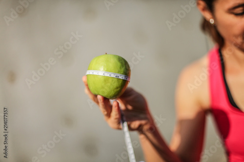 nutrition expert holding a green apple with measure tape for diet motivation © shellygraphy
