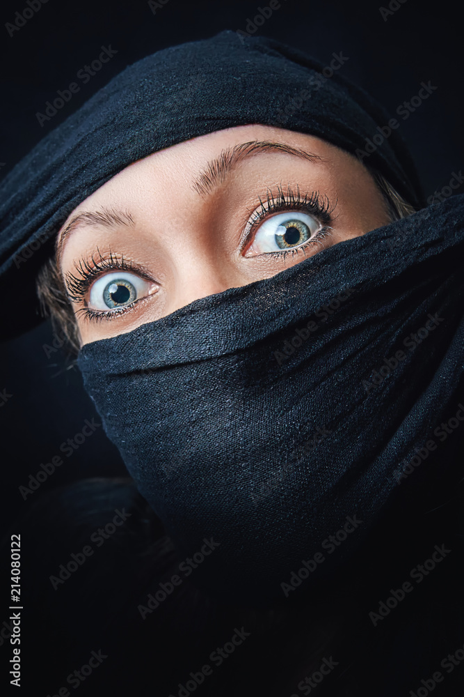 Woman face close up with only eyes visible, rest of the face is covered with black scarf