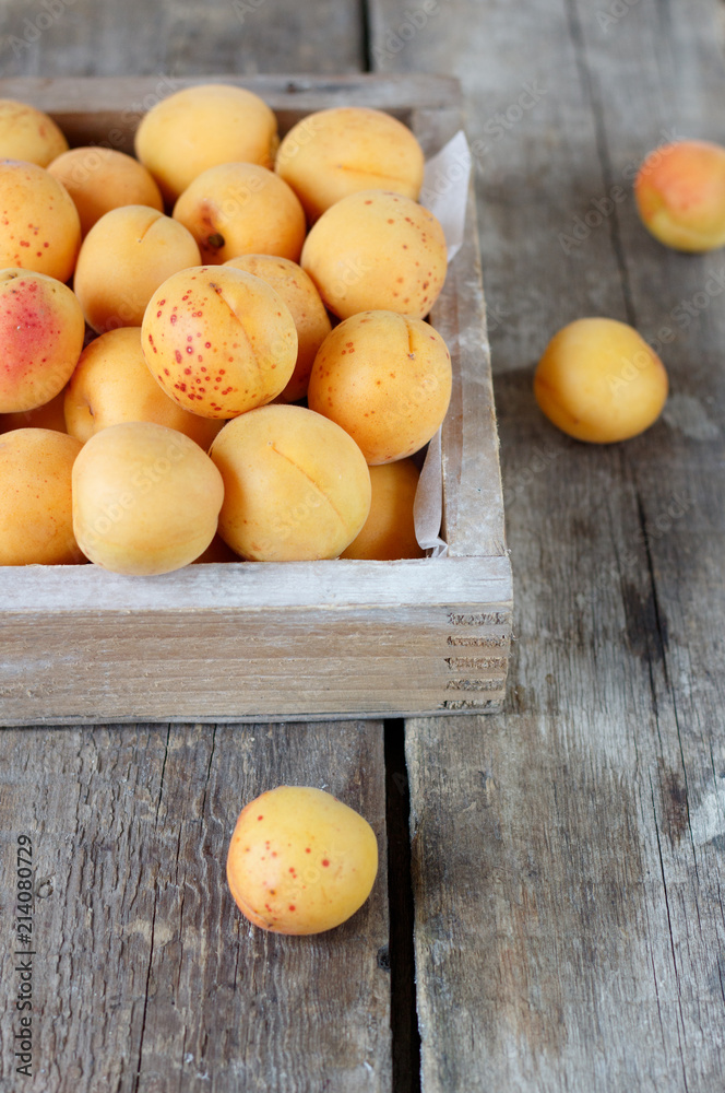 Ripe apricots in a wooden box on a wooden table 