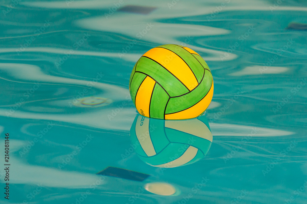 Yellow and green water polo ball with reflection in swimming pool