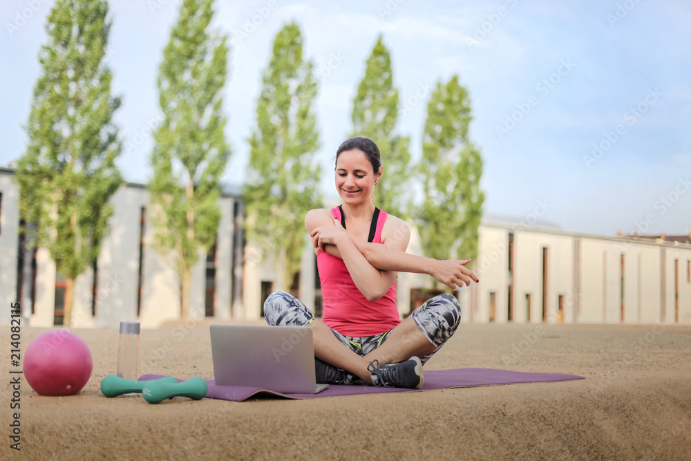 fit woman watching online fitness program and doing workout infront of a laptop on a mat