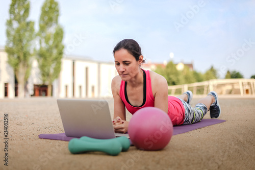 fit woman watching online fitness program and doing workout infront of a laptop on a mat photo