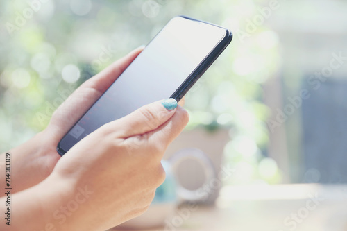 Close up on woman hand holding smartphone trading stock and data in coffee shop background business concept