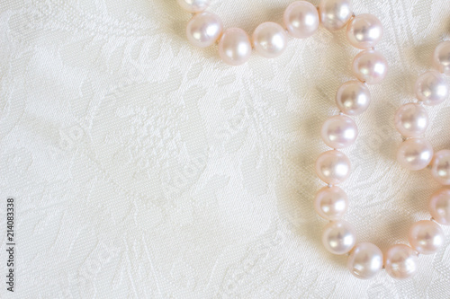 White silk satin background close up with pearl necklace - Top view photo