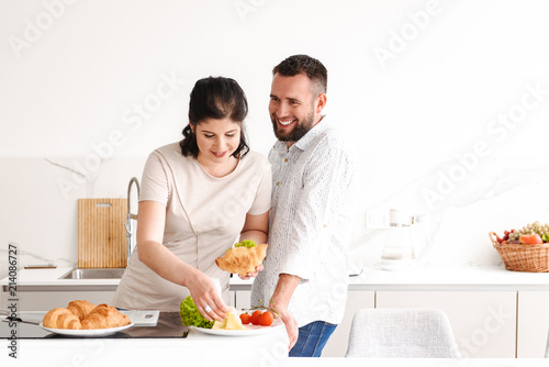 Portrait of beautiful family happy man and woman cooking, and having breakfast in bright kitchen