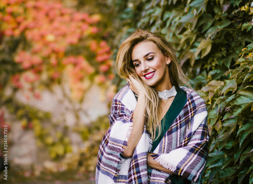 Smiling happy pretty girl at park. Cold outside, girl with blanket. Autumn season. Copy space on left Smiling happy pretty girl at park. Cold outside, girl with blanket. Autumn season. Copy space on left