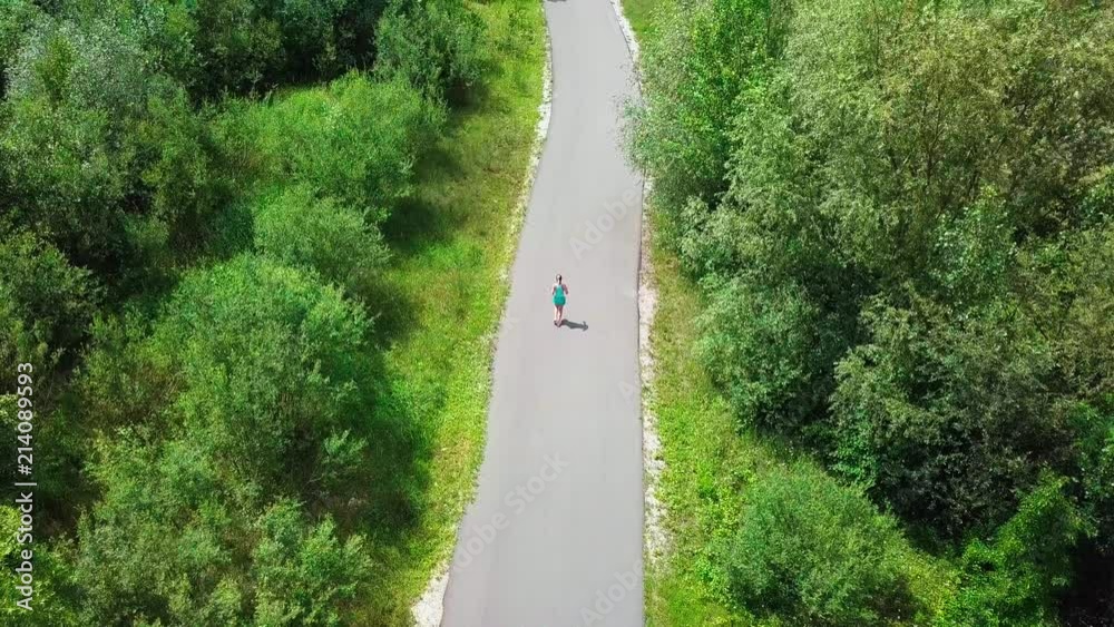 Aerial View Running woman on the road mountain. Runner is jogging in summer sunny day around trees and mountains background under sun light with blue sky, Drone 4K Video Aerial View Running woman on the road mountain. Runner is jogging in summer sunny day around trees and mountains background under sun light with blue sky, Drone 4K Video