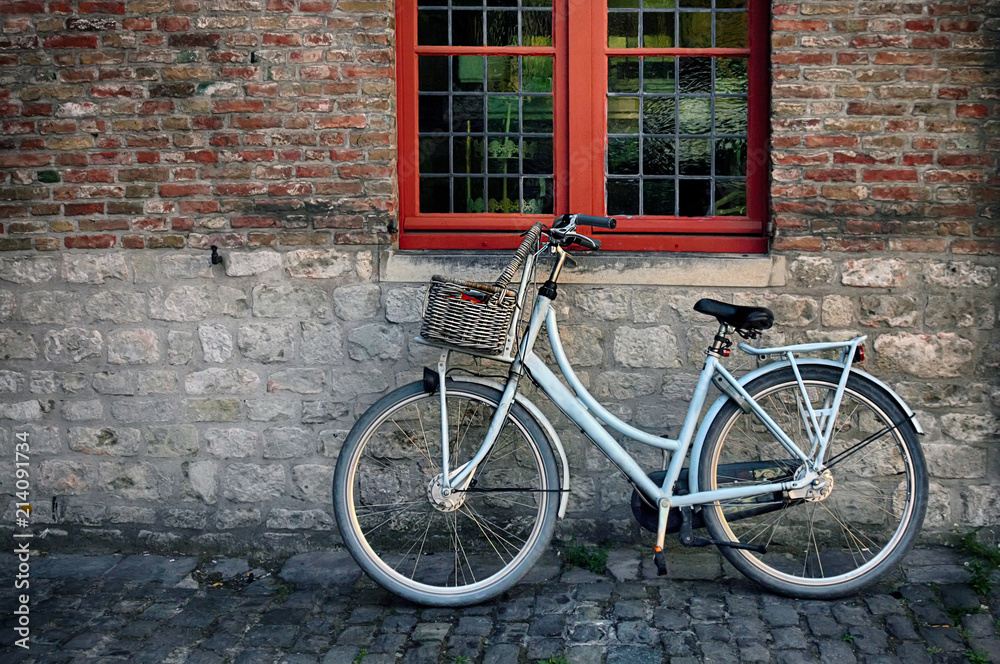 Bicycle with basket in fromt of old wall with red window