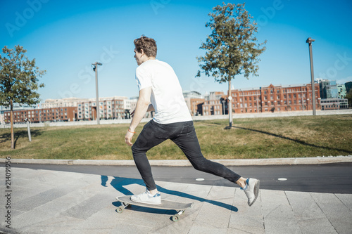 Young attractive man riding longboard in the park.