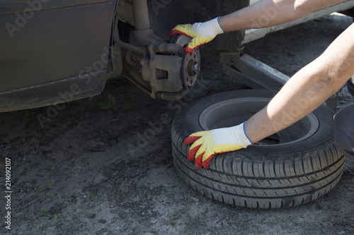 Mechanic changing wheel on car with impact wrench , Mechanic changing car wheel in auto repair shop , Close up of mechanic changing wheel on car with pneumatic wrench