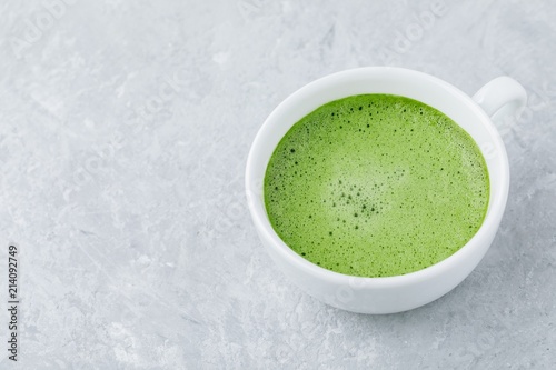 Japanese matcha green tea latte in white cup on gray background