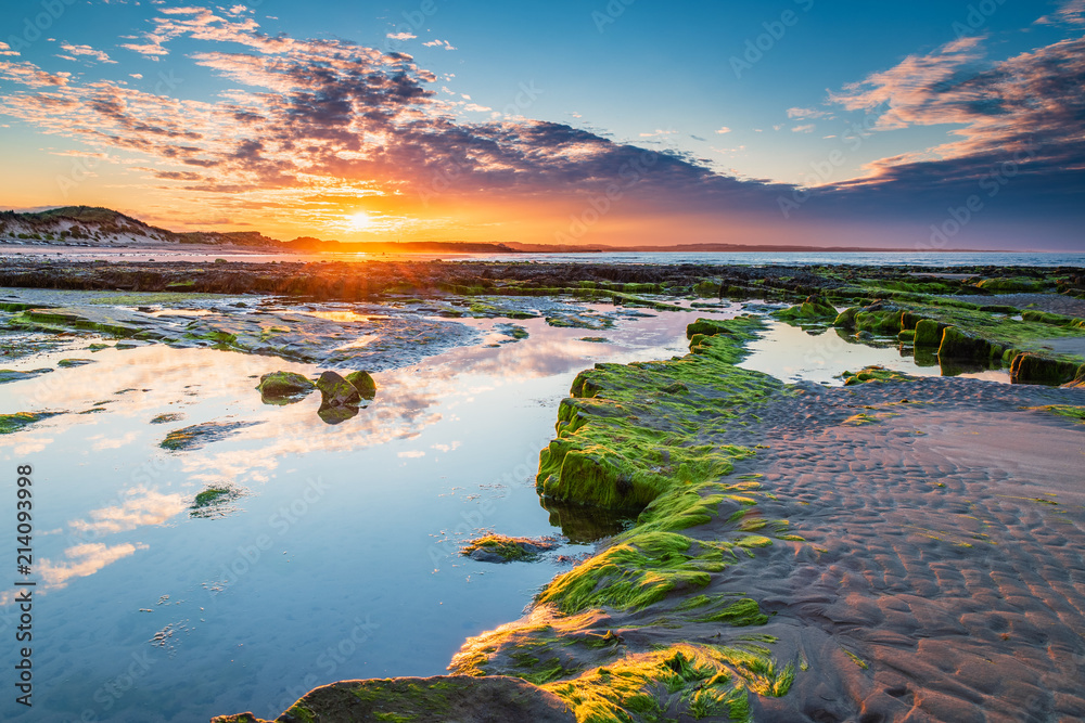 Naklejka premium Zachód słońca nad Low Hauxley Rockpool / Low Hauxley Beach na wybrzeżu Northumberland obejmuje zarówno piaszczyste obszary, jak i skaliste wychodnie