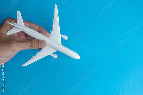 Copyspace of hand holding white toy airplane on blue background