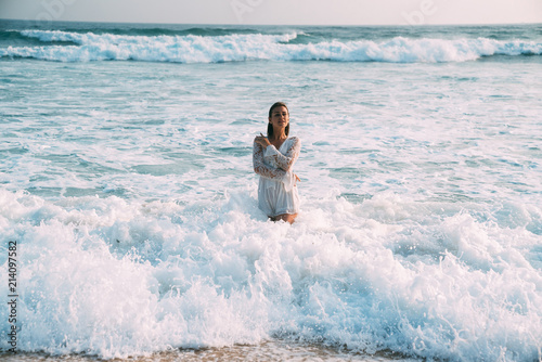 The brunette in a beautiful suit is waist-deep in seawater  and white foam. The concept of relaxation  beach  bathing in the sea  sunbathing  people.