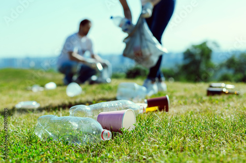 Environmental protection. Silhouette of volunteers that holding plastic bag while gathering litter from park