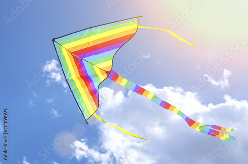 colorful flying kite flying in the sky with clouds, in the sunlight
