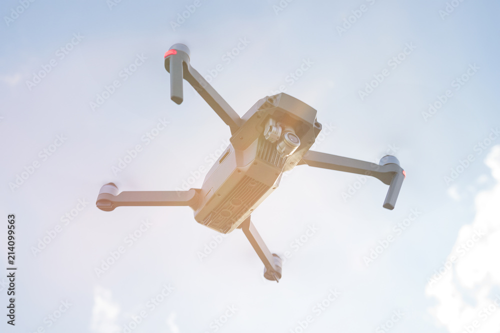 Flying quadcopter drone with Action Camera in the air under blue sky Flying quadcopter drone with Action Camera in the air under blue sky