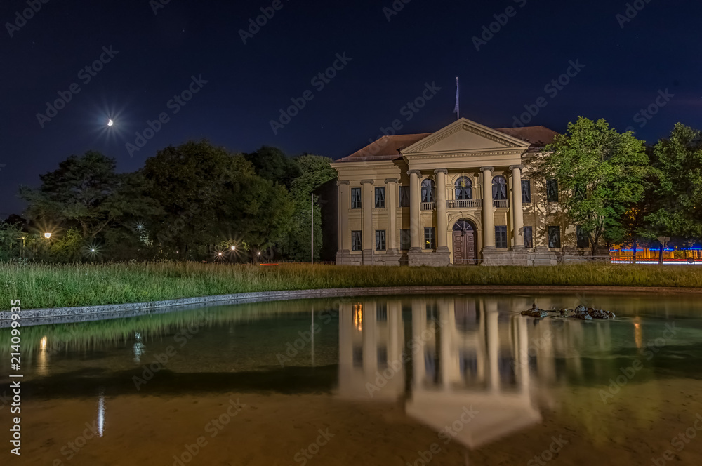 München bei Nacht - Villa am See, das Carl Preis Palais am Rande des Hofgartens, der Amtssitz des Bayrischen Ministerpräsidenten mit einem Teich im Vordergrund und dem Mond Hintergrund München bei Nacht - Villa am See, das Carl Preis Palais am Rande des Hofgartens, der Amtssitz des Bayrischen Ministerpräsidenten mit einem Teich im Vordergrund und dem Mond Hintergrund