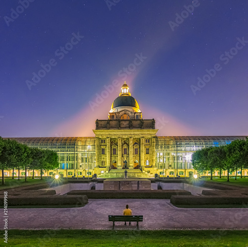 München bei Nacht - die neue Staatskanzlei in einem wunderbaren Licht mit einem auf einer Bank sitzenden Mann im Vordergrund photo