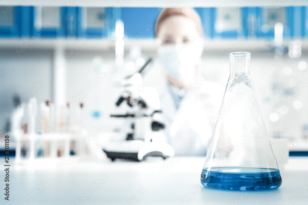 Organic chemistry. Selective focus of a flask being filled with chemical reagent standing on the table in the lab Organic chemistry. Selective focus of a flask being filled with chemical reagent standing on the table in the lab