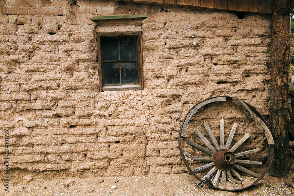 Old Western Adobe Building and Wooden Wagon Wheel