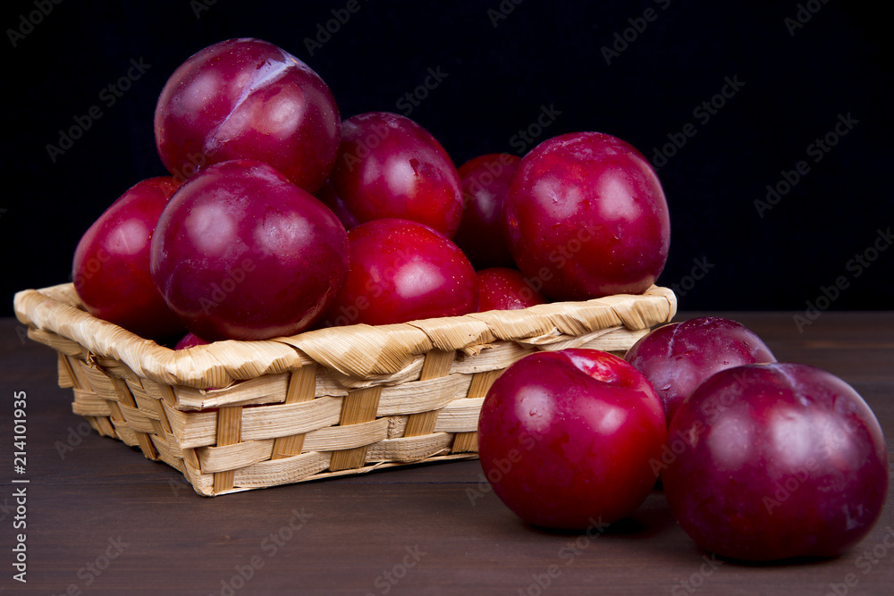 ripe plum in a basket on a wooden table dark background ripe plum in a basket on a wooden table dark background