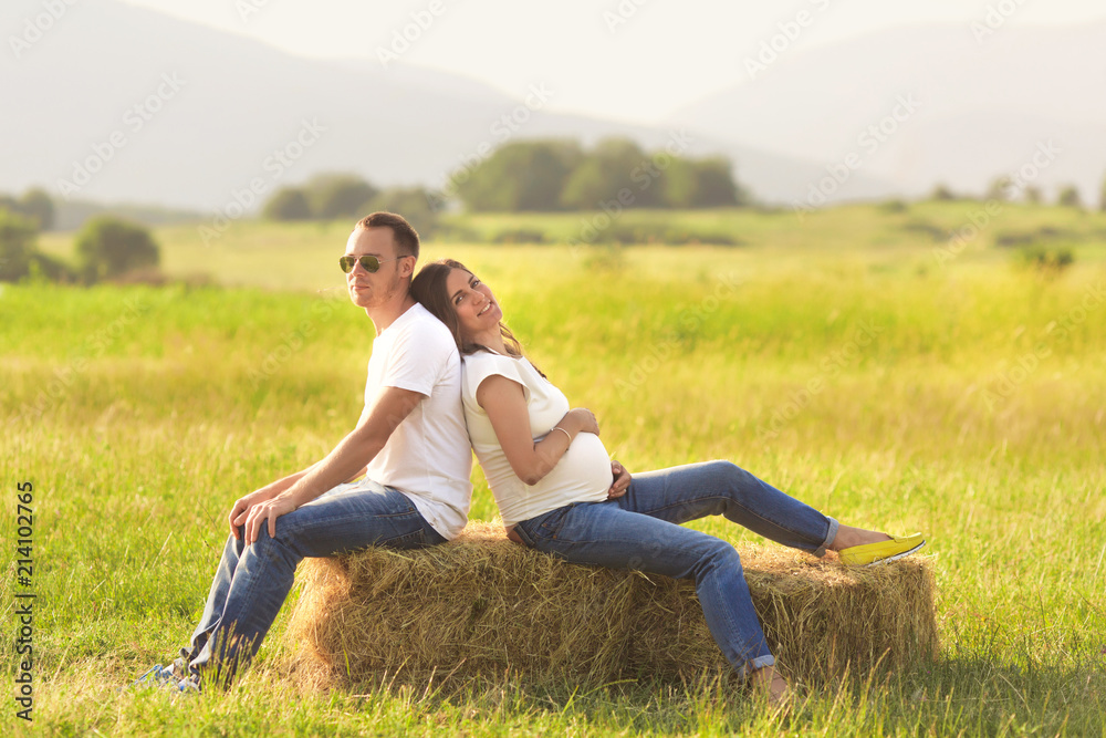 Young pregnant woman with her husband enjoying the nature wearing casual and style jeans and white t-shirt. Young pregnant woman with her husband enjoying the nature wearing casual and style jeans and white t-shirt.