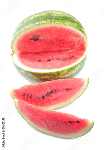 A large ripe watermelon and two slices are next to a white background. isolated