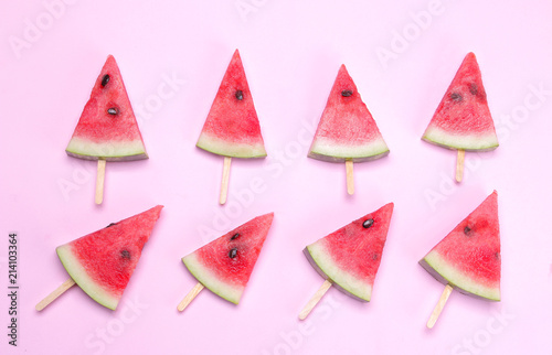 Many different bright ripe slices of watermelon on a stick on a bright pink background. Top view