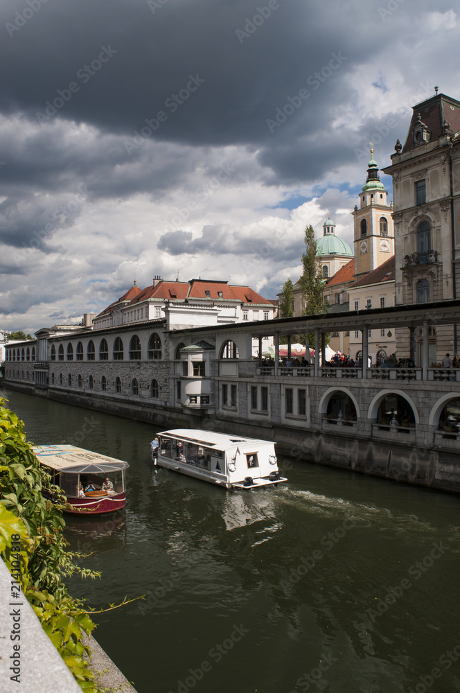 Obraz premium Slovenia, 24/06/2018: vista dello skyline del centro di Lubiana, la capitale slovena, con una barca turistica in navigazione naviga sul fiume Ljubljanica